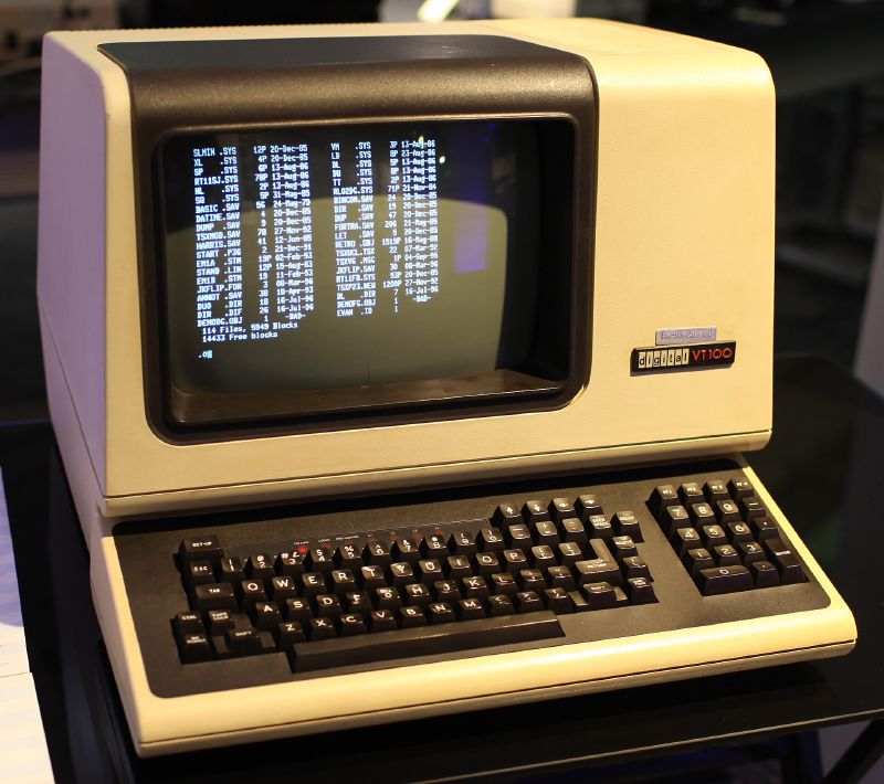 A DEC VT100 terminal showing a column of text on its screen above a black keyboard.